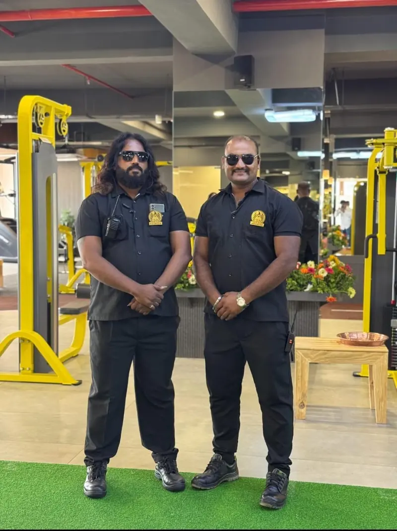 Two guards in black uniforms standing inside a gym