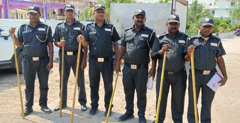 A group of guards in grey uniforms holding batons