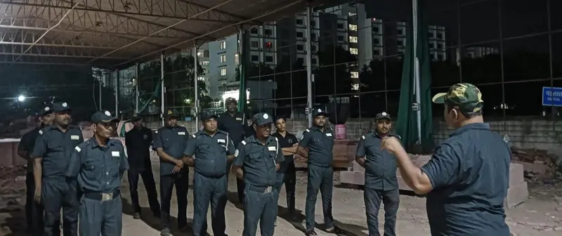 A group of guards in uniform standing in front of tall buildings at night