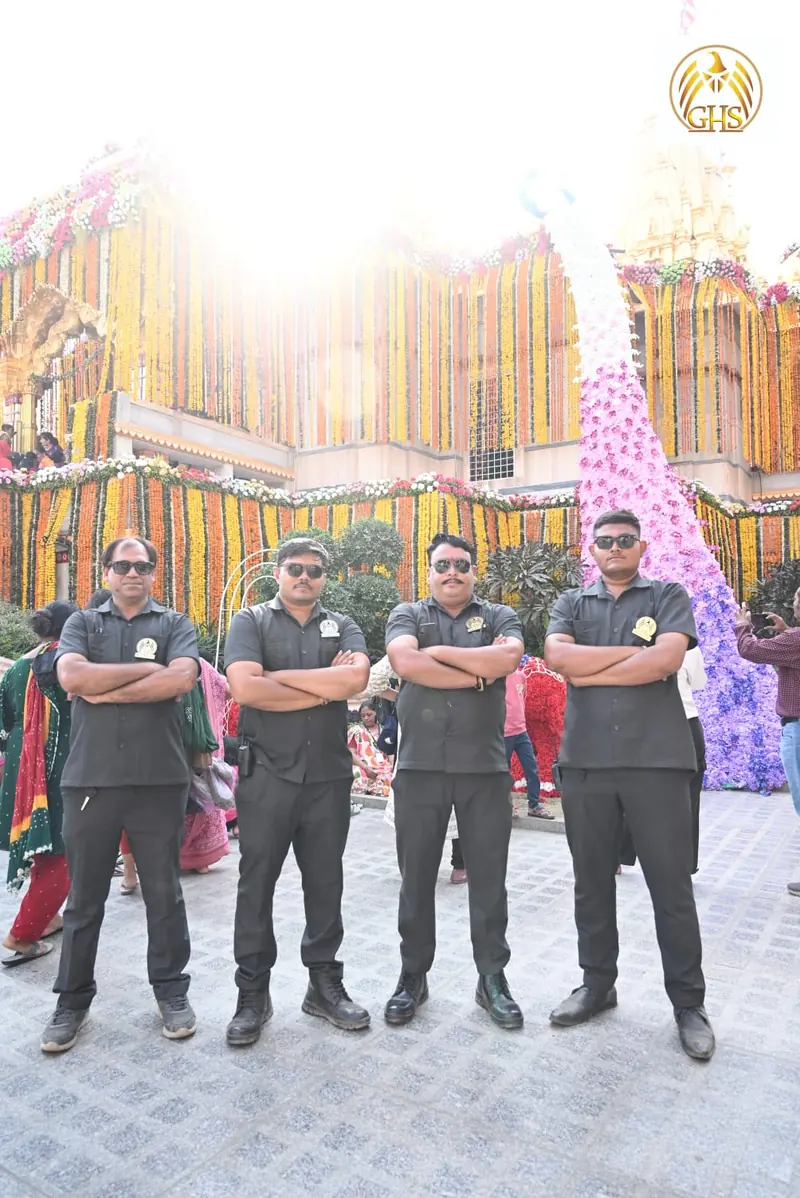 Four guards with folded arms standing in front of a flower-decorated structure