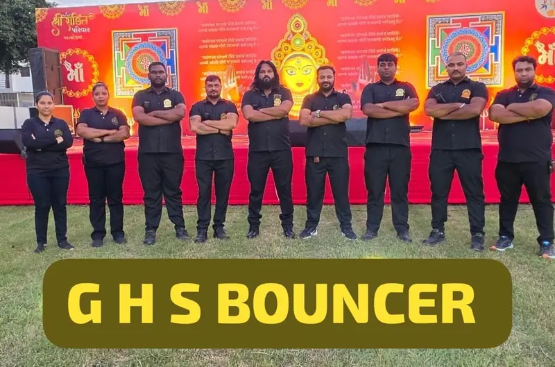 Eight GHS team members in black standing in a row in front of a red decorated backdrop with the text GHS Bouncer